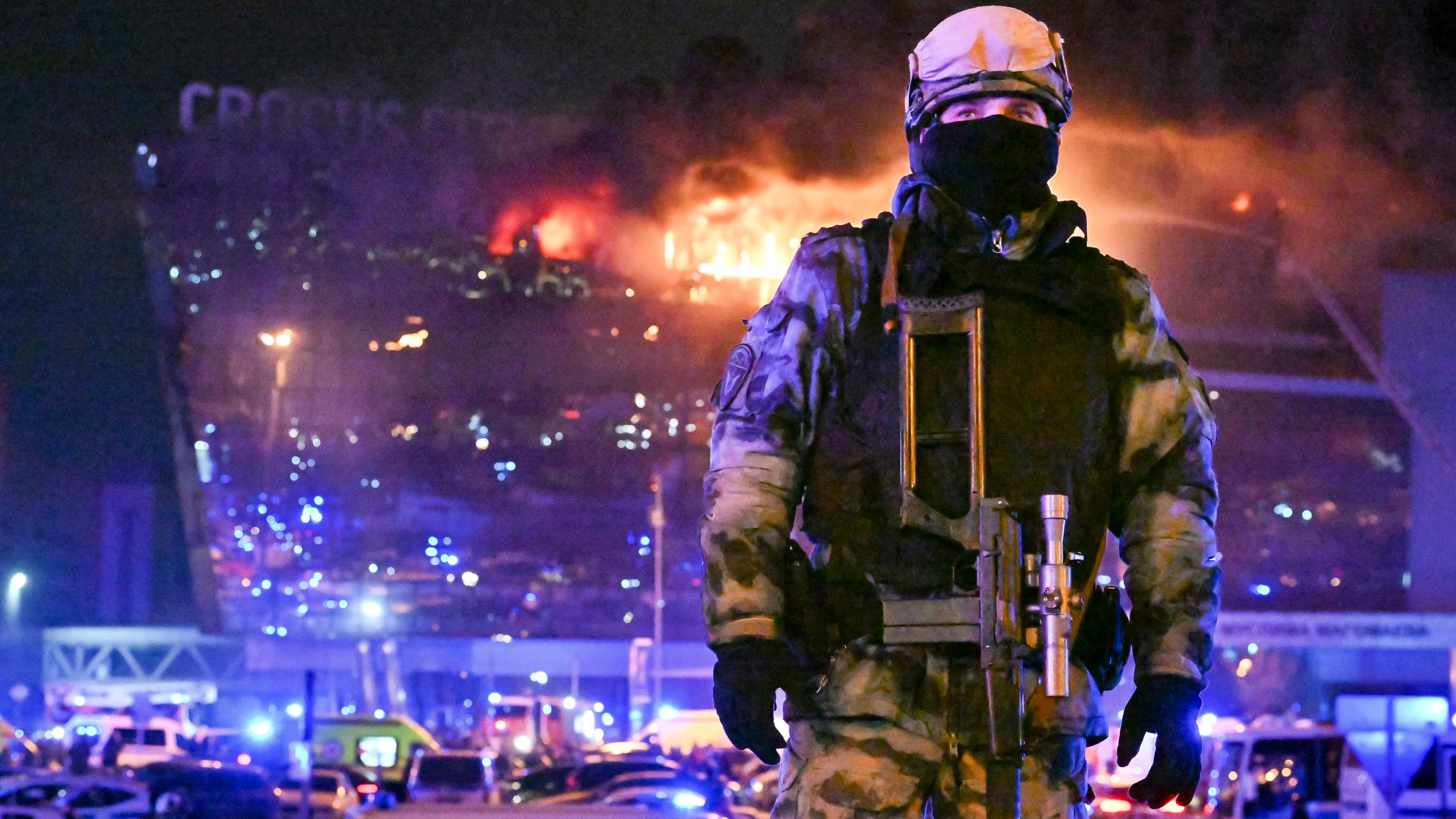 A Russian Rosguardia (National Guard) servicemen secures an area as a massive blaze seen over the Crocus City Hall on the western edge of Moscow, Russia, Friday, March 22, 2024. Several gunmen have burst into a big concert hall in Moscow and fired automatic weapons at the crowd, injuring an unspecified number of people and setting a massive blaze in an apparent terror attack days after President Vladimir Putin cemented his grip on the country in a highly orchestrated electoral landslide. (AP Photo/Dmitry Serebryakov)